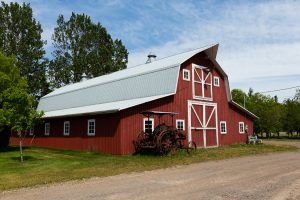 vintage rusted tractor in front of red wooden barn