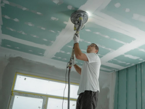 man sanding drywall ceiling