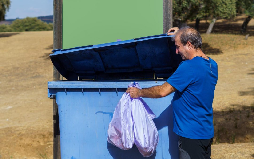 man throwing bag of trash in dumpster