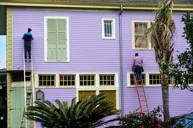 men on ladders installing siding on house