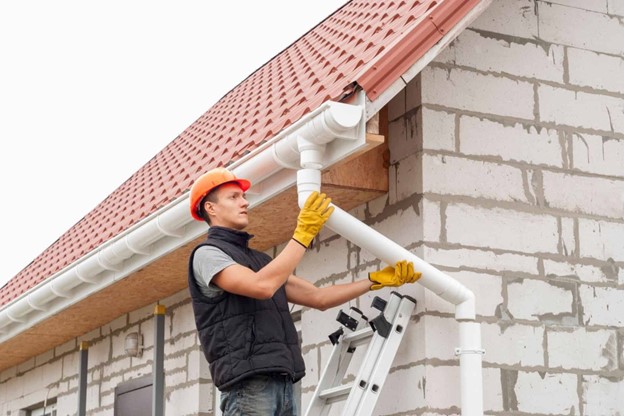 man installing gutter on house