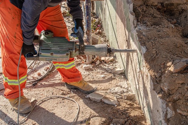 man using jack hammer on concrete wall