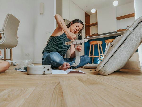 woman sitting on floor putting furniture together