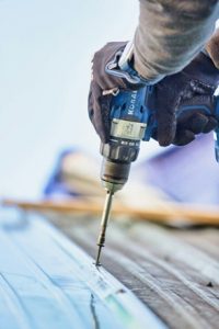 man using drill instlaling roof