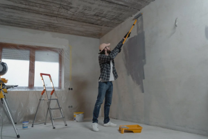 man rolling paint on wall