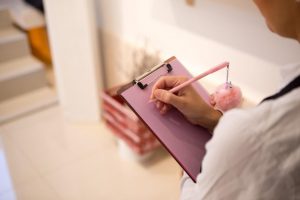 woman writing on pink clipboard