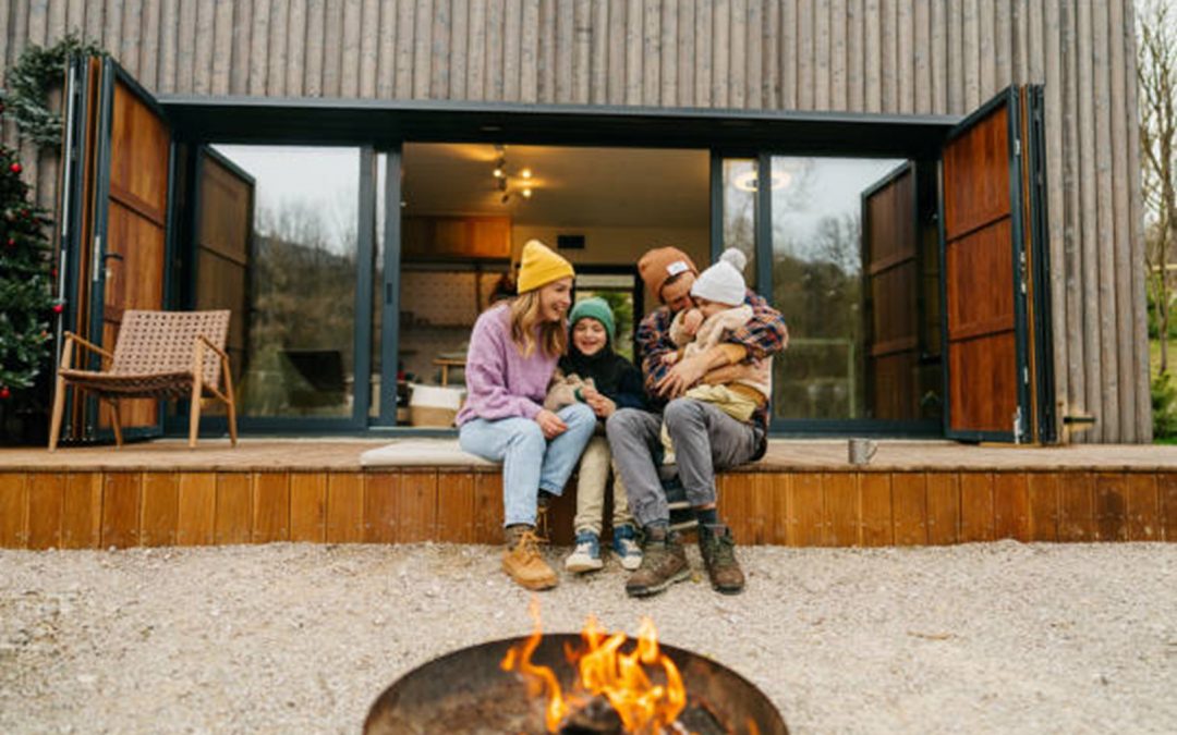 family sitting outside home in chilly weather with fire in firepit