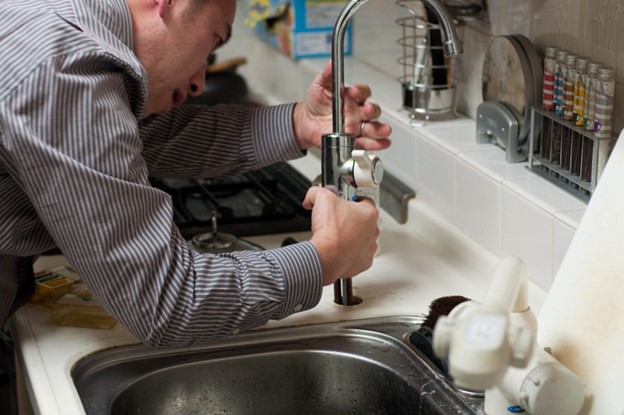 man installing kitchen faucet