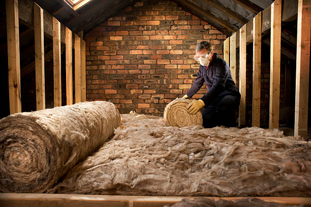 man rolling out loft insulation wearng safety mask