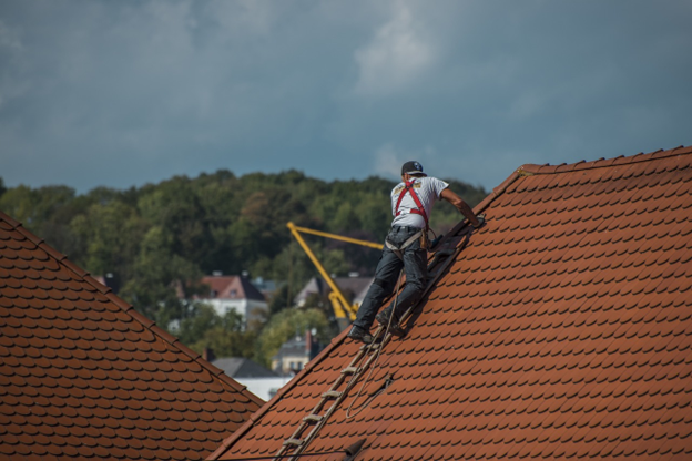 man repairing roof wearing safety harness