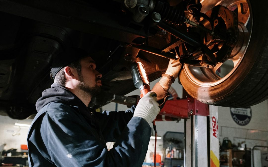 man working under car looking at brakes