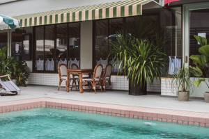 pool and patio seating with green and white striped shade awning