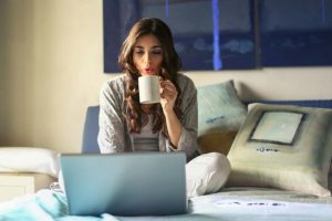 woman drinking coffee looking at computer