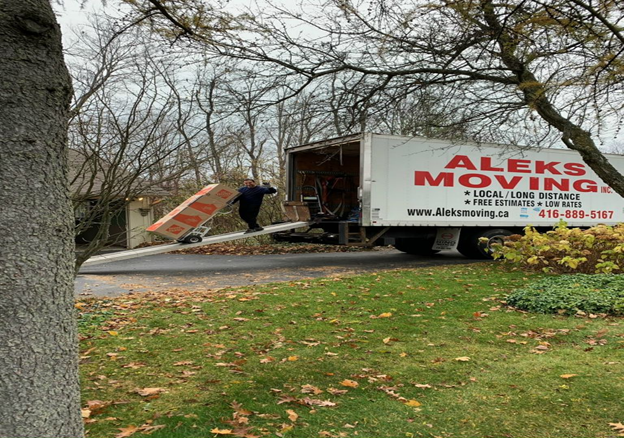 man wheeling packing boxes off mover's truck