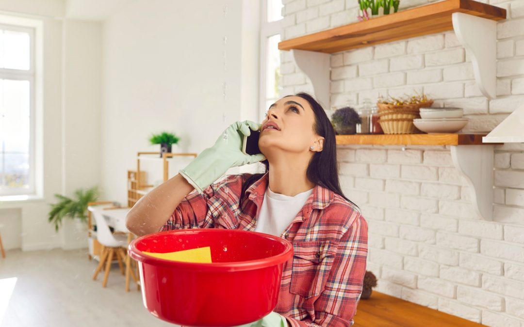 woman looking at water leaking from roof