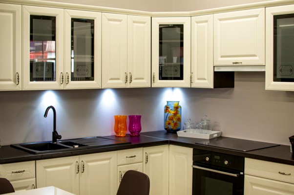 cream color kitchen cabinets with black countertops and appliances