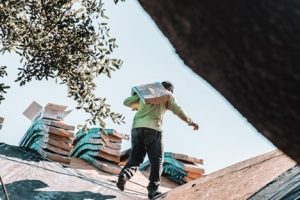 man carrying shingles preparing for roof installation