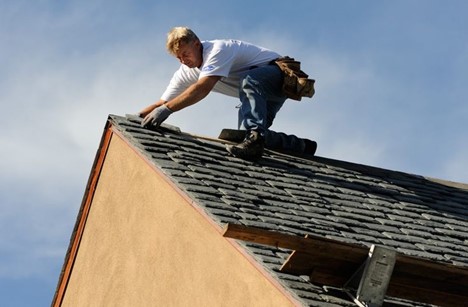 roofer on peak of roof making repairs