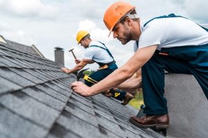 two roofers nailing asphalt shingles