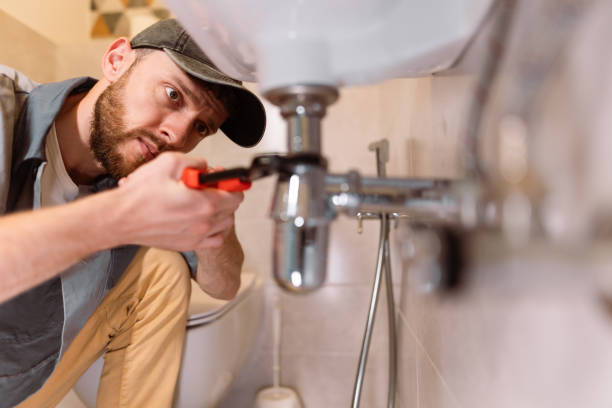 plumber using pipe wrench under sink