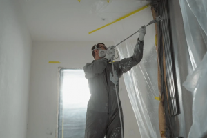 painter covering areas with plastice to spray paint