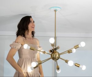 woman installing retro mid century modern light fixture on ceiling