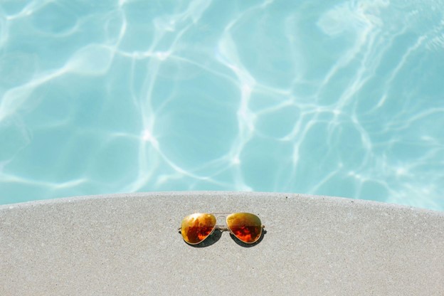 sunglasses next to clear blue pool water