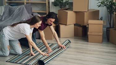 couple unpacking and rolling out a rug