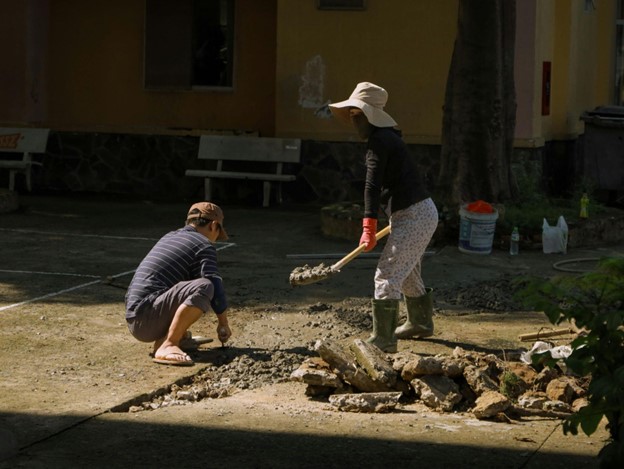 two people with shovels digging building foundation