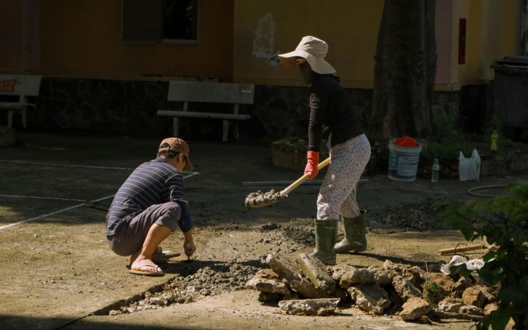 man digging up foundation near young boy