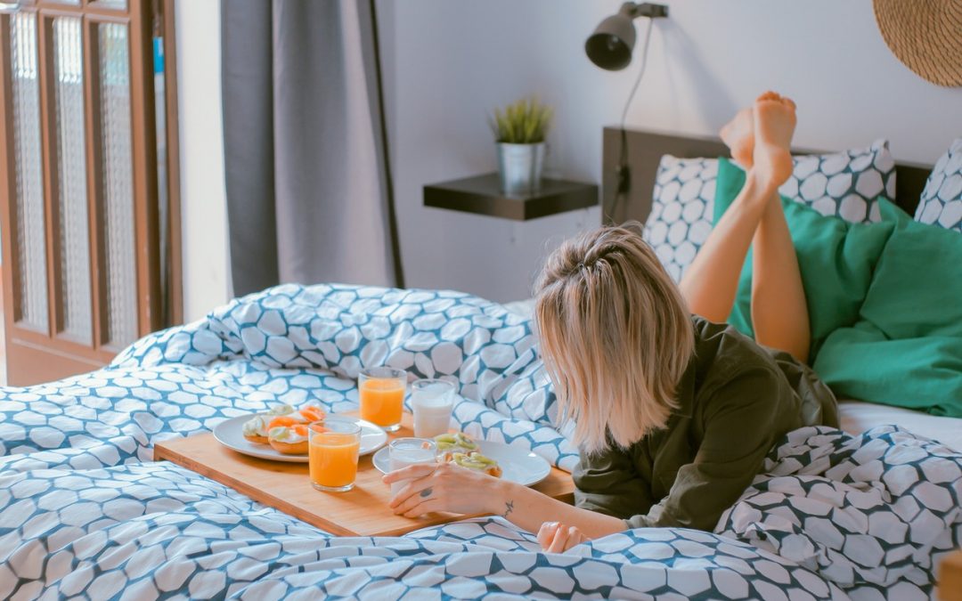 woman lounging on bed with breakfast