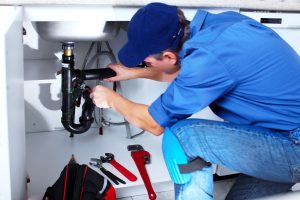 plumber fixing pipes under sink