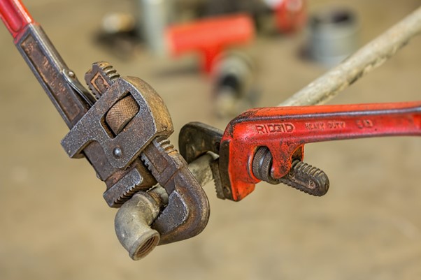 plumber using wrench to repair pipe lead