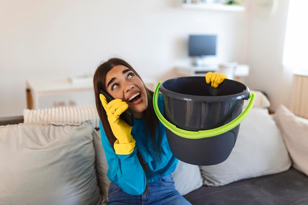 woman with bucket catching water from roof leak