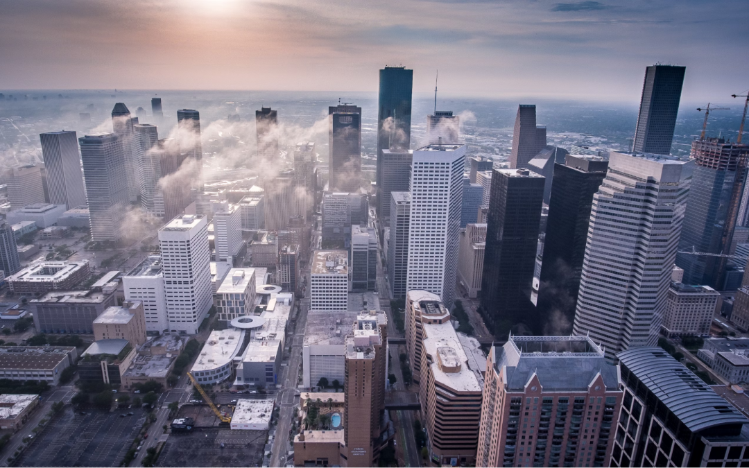 photo of a large city scape from the sky with the sun in the background causing glare