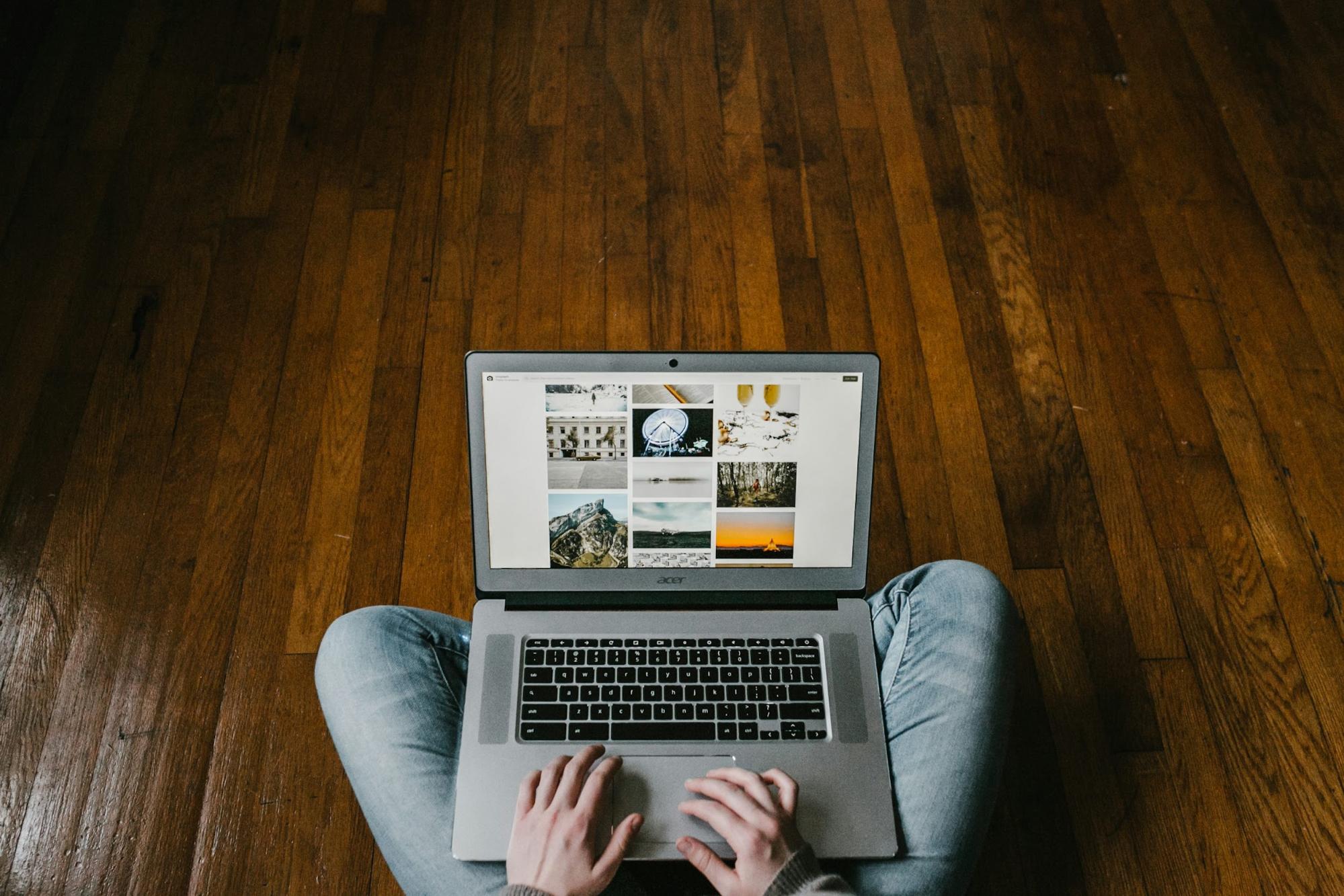 silver laptop in someones lap on hardwood floor