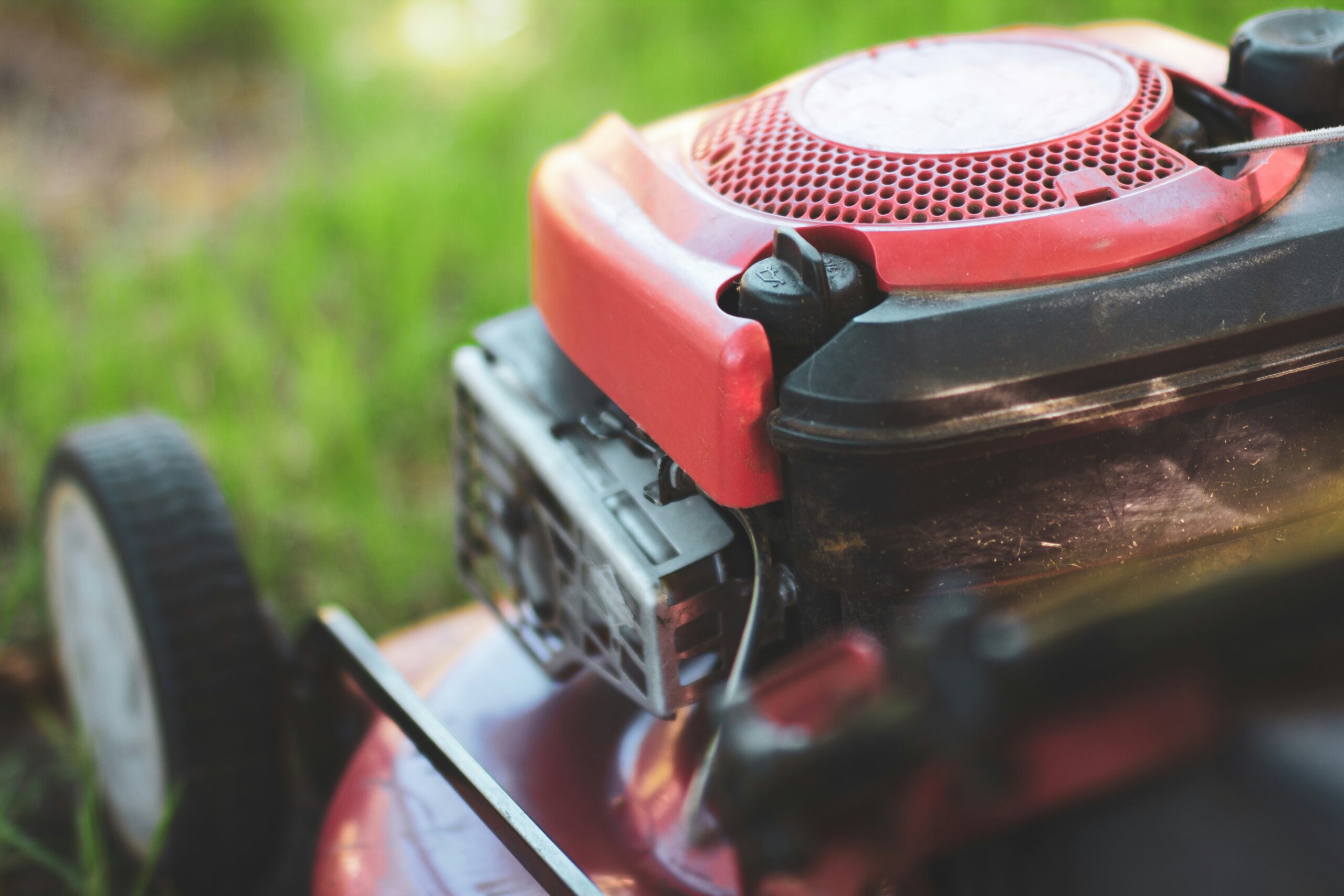 red lawn mower sitting on top of a lush green field