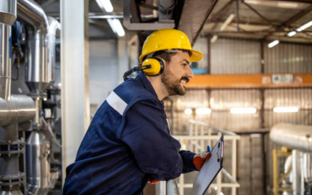 man in working gear leaning on rail with clipboard