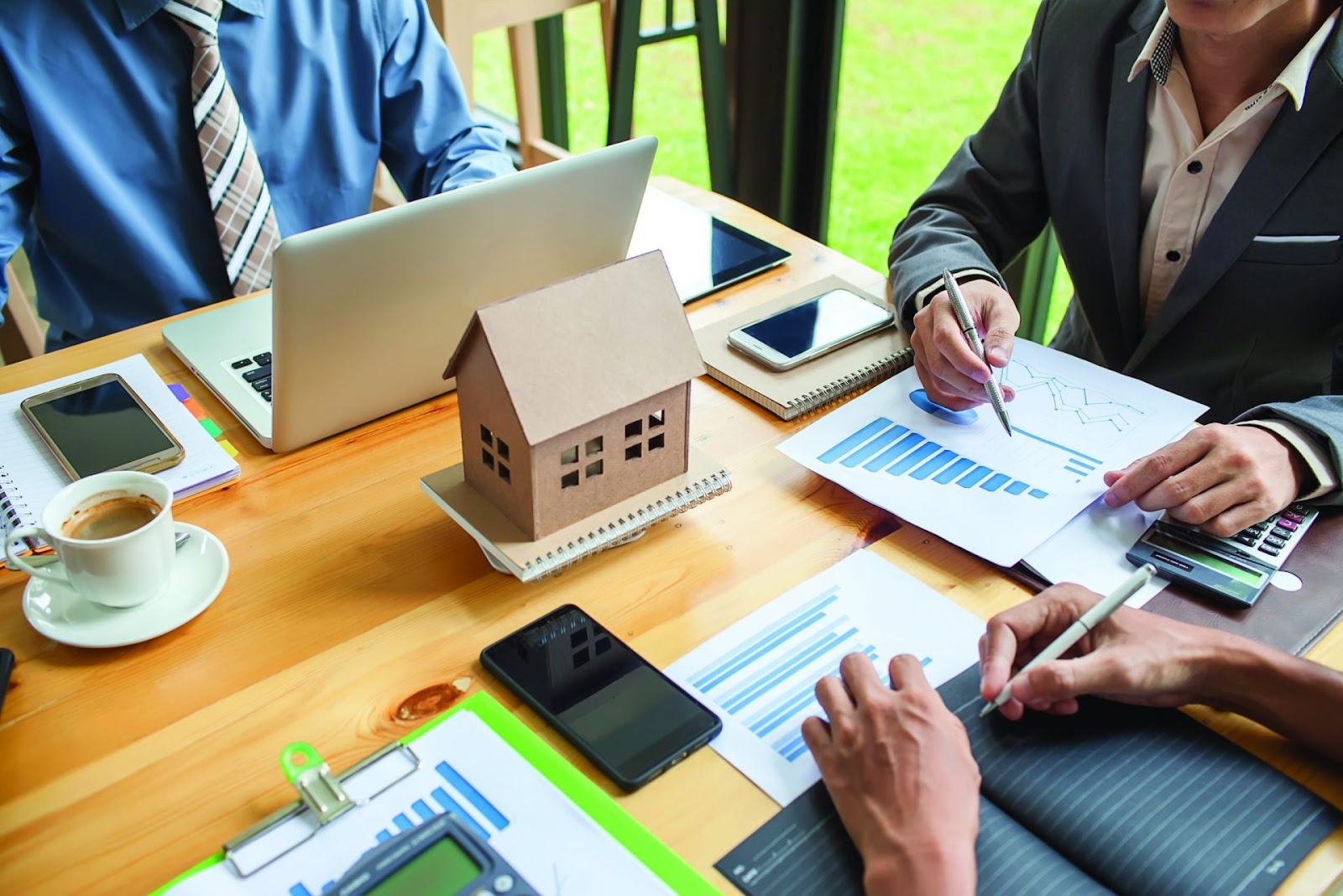 meeting at a desk with a model house in the center