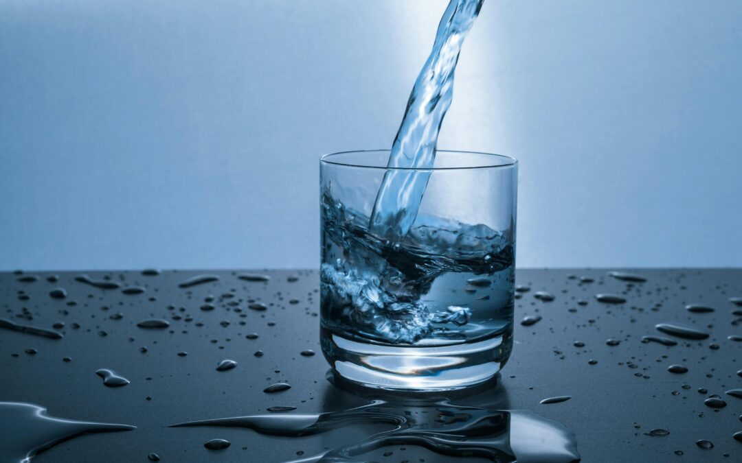 clear glass being filled with water on a dark wet countertop