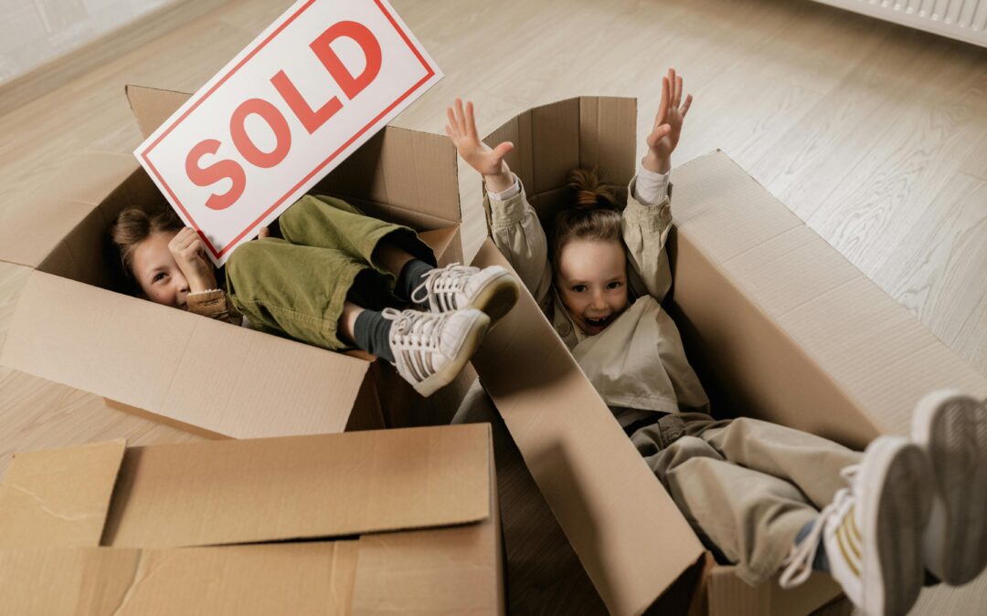 kids playing in boxes while moving with a sold sign in hands