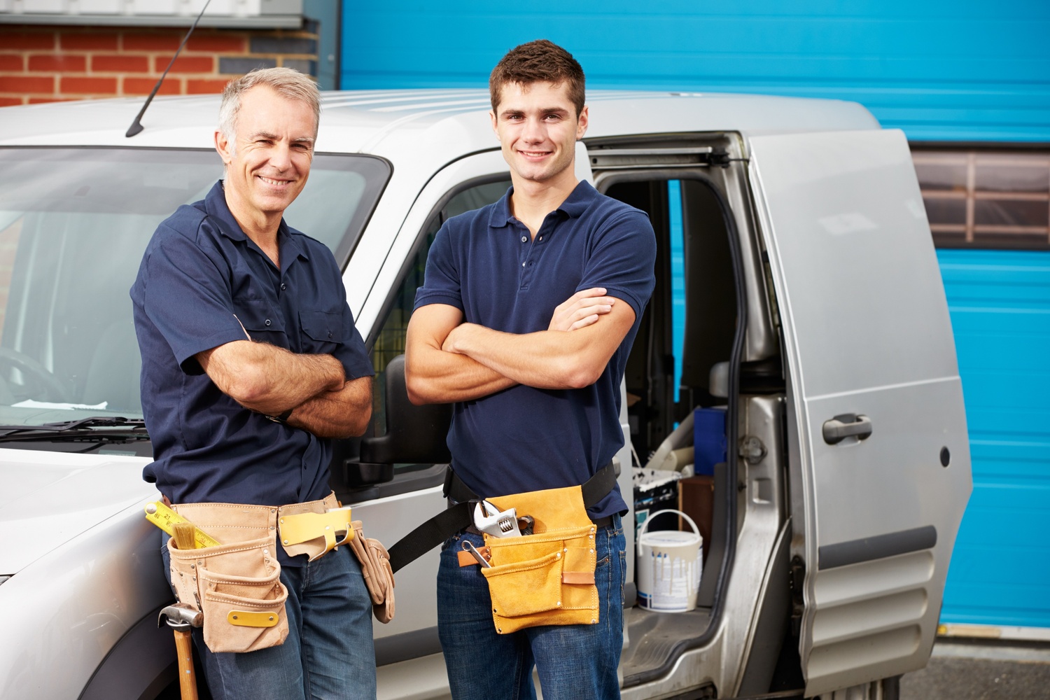 Plumbers posing for a photo next to their van