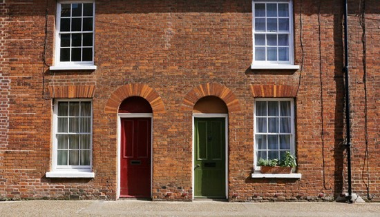 brick building with red and green front doors brick sided building with two colorful entry doors