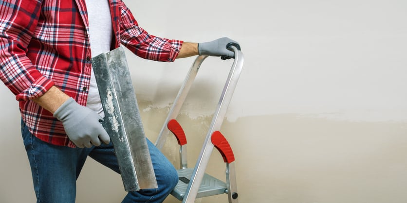 Home improvement, renovation – handyman plastering wall using construction trowel. Panoramic banner with copy space.
