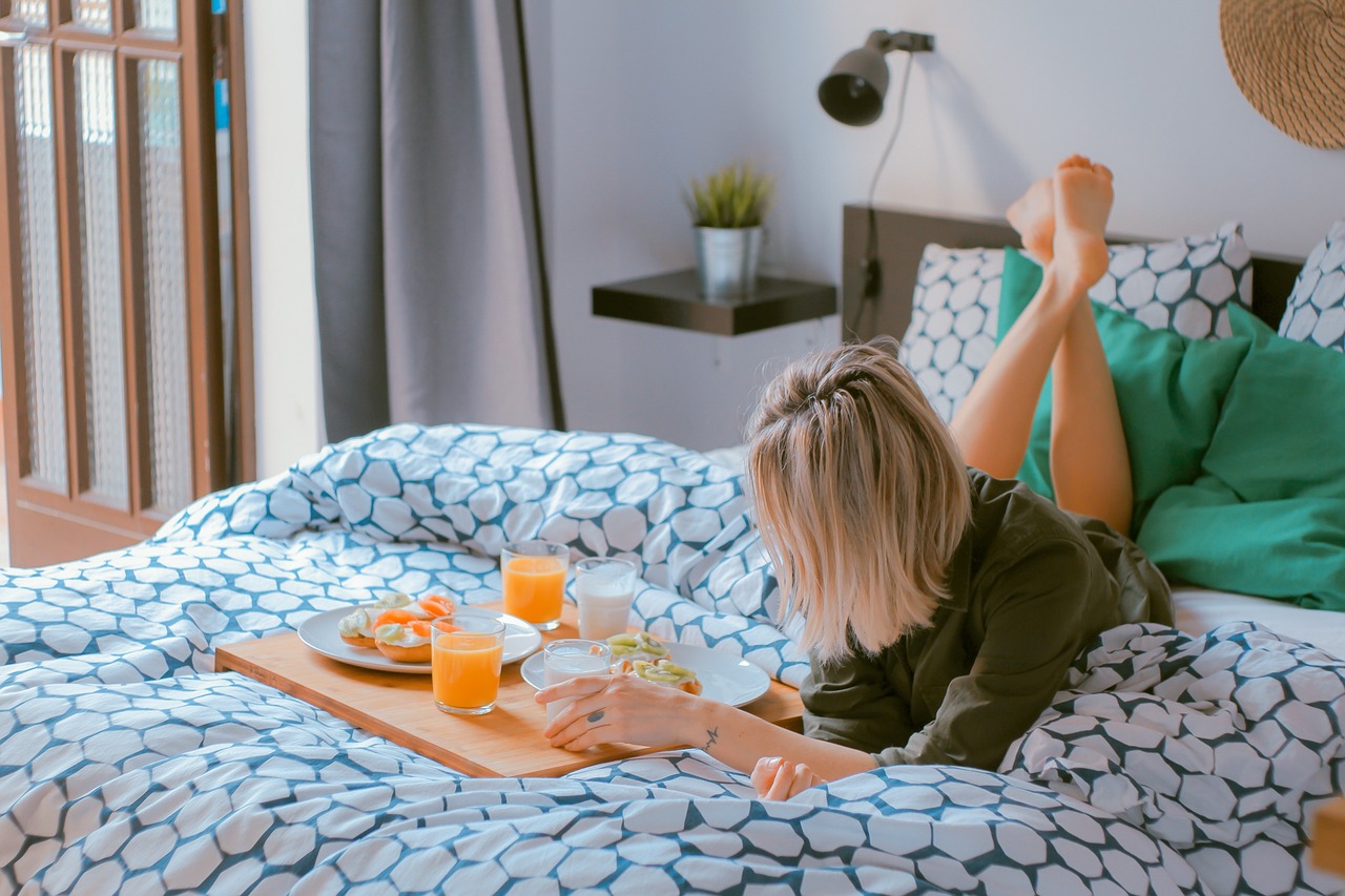 woman lounging on bed with breakfast