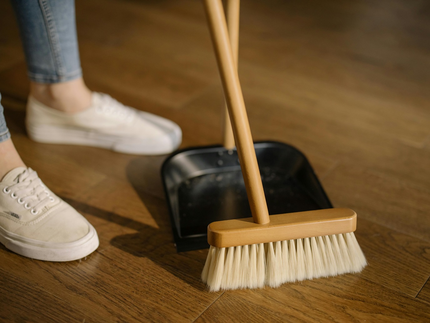 person using broom and dust pan house cleaner sweeping floor