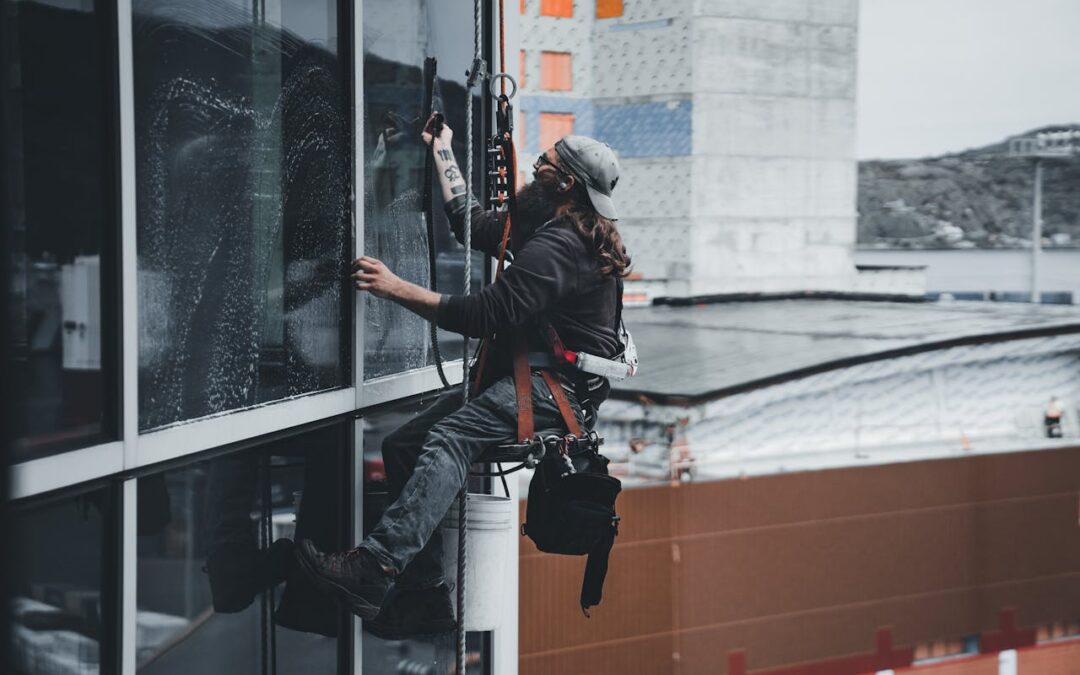 side view of a man in a climbing rig doing window cleaning on a building