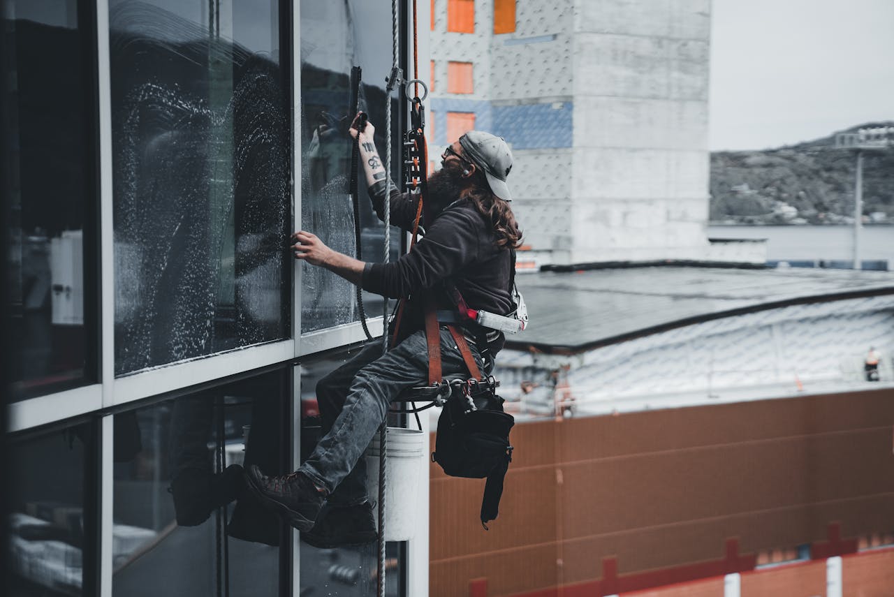 side view of a man in a climbing rig doing window cleaning on a building